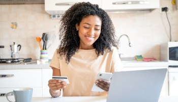 One happy black woman making credit card purchase from home