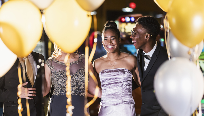 Teenage couple with friends having fun at prom