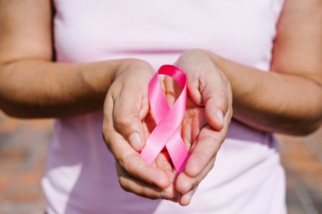 A woman holding a pink ribbon to signify Breast Cancer Awareness