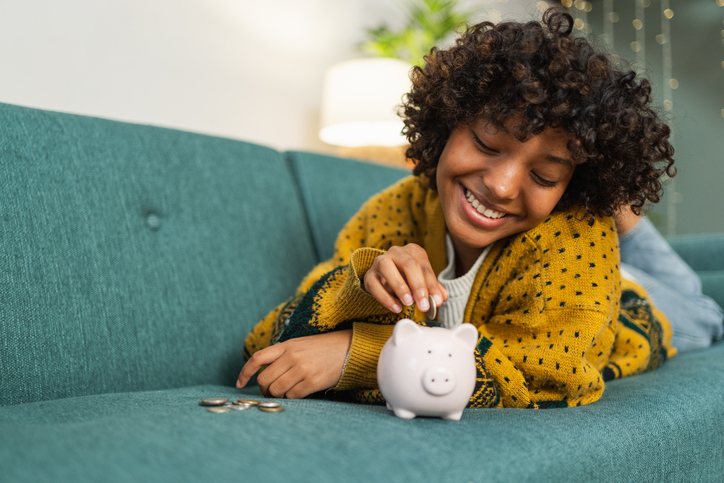 Saving money investment for future. African American girl putting money coin in pink piggy bank. Saving investment budget business wealth retirement financial money banking concept.