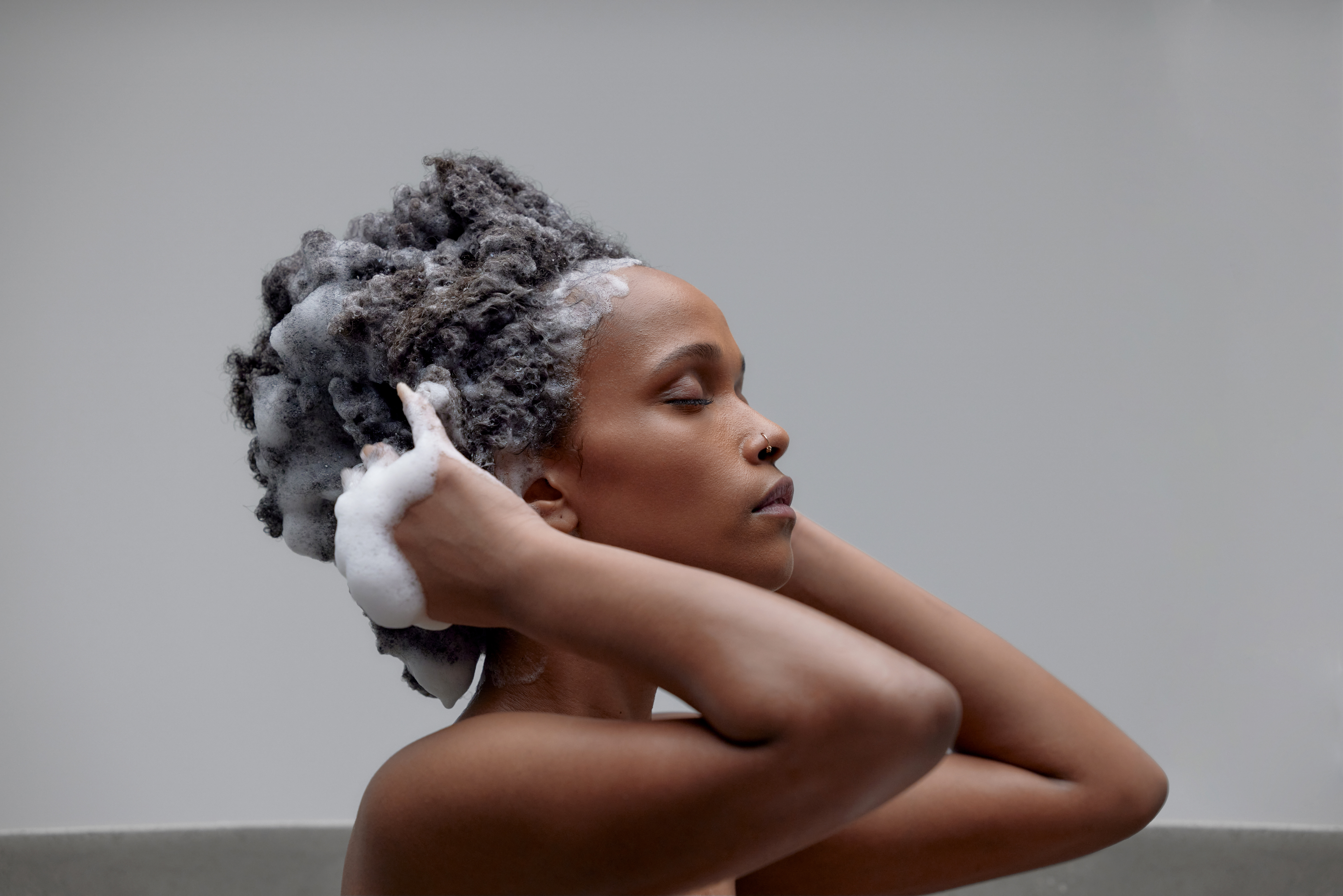 Black woman washing her hair using Beyoncé Cécred products Haircare collection