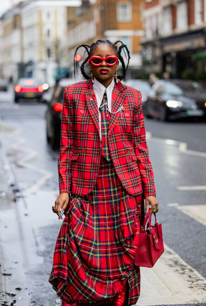 fashionable Black women dressed in red sunglasses with red plaid pattern skirt, blazer, and tie