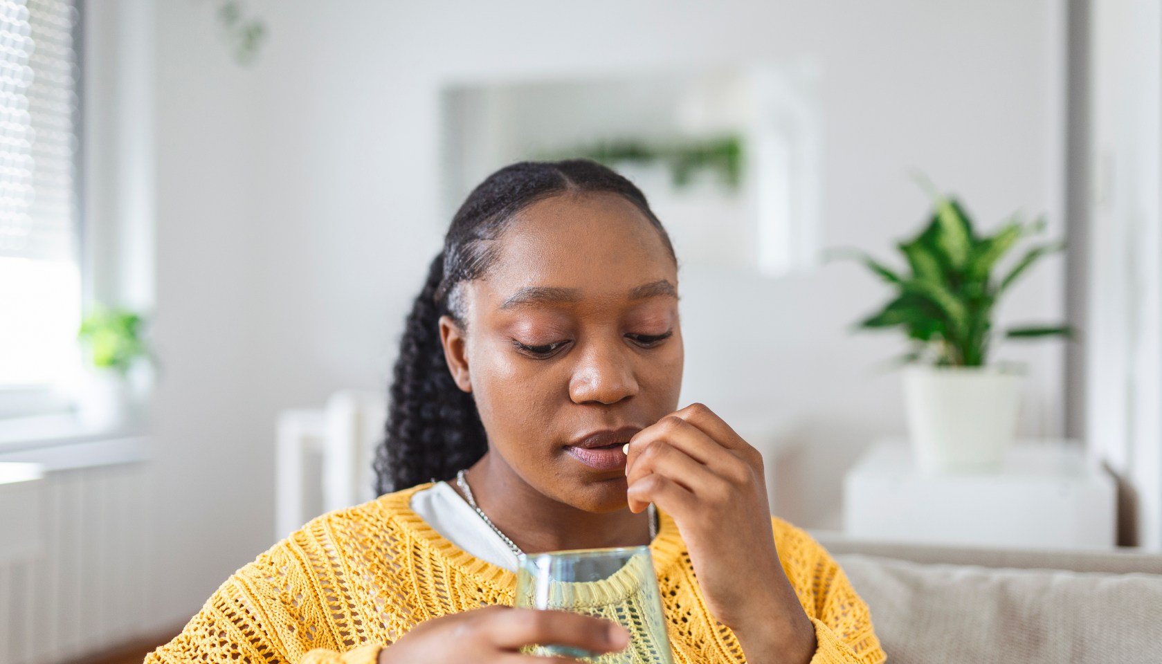 A Black woman taking a supplement