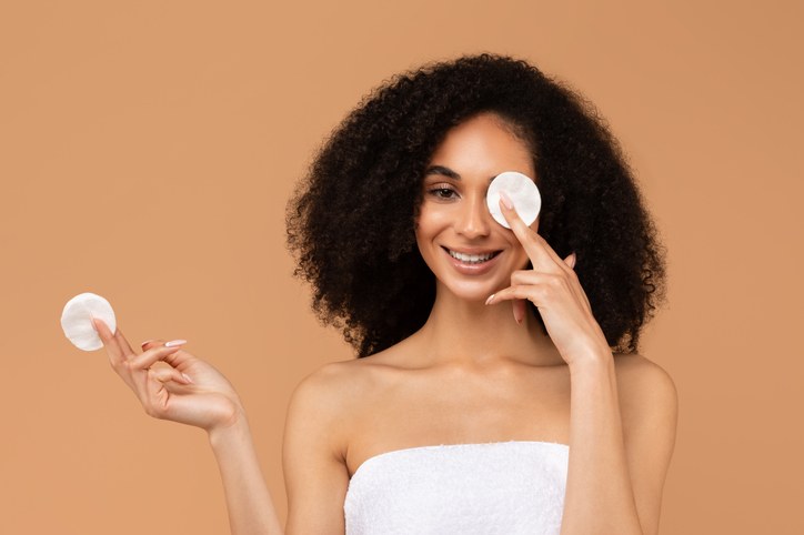 Smiling Woman Applying Cotton Pad To Eye