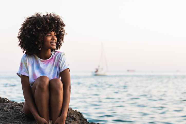 Delighted ethnic woman laughing at seaside