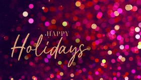 Happy Holidays Christmas Calligraphy Script Text. Christmas Gold Glitter Blured Bokeh Light Red Background. Happy Holidays text with sparkling gold letters on a vibrant red and pink bokeh background.