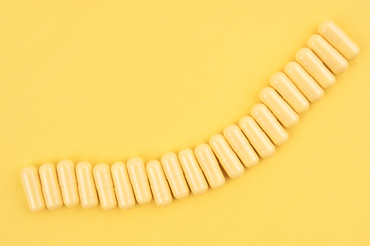 Many yellow pills capsules on yellow color background.