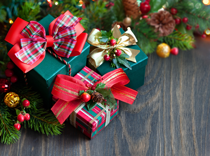 Christmas gift boxes. Close-up of holiday presents with plaid ribbons, pine branches, and ornaments on a wooden surface.