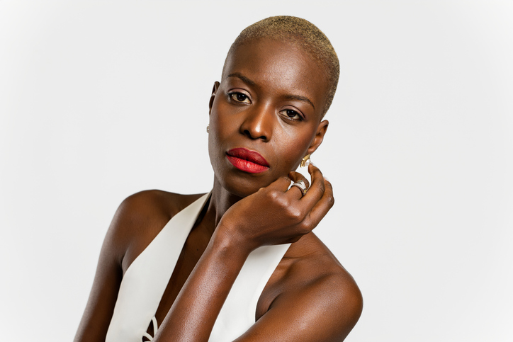 Confident young woman with short blonde hair and red lipstick posing in studio
