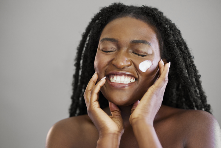 Joyful Black Woman Laughing with Skincare Cream Swatch on Her Face