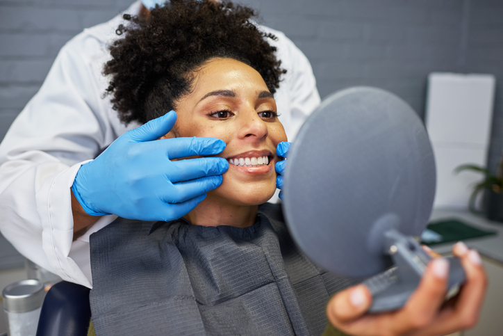 Patient Smiling in Mirror During Dental Examination at Modern Clinic
