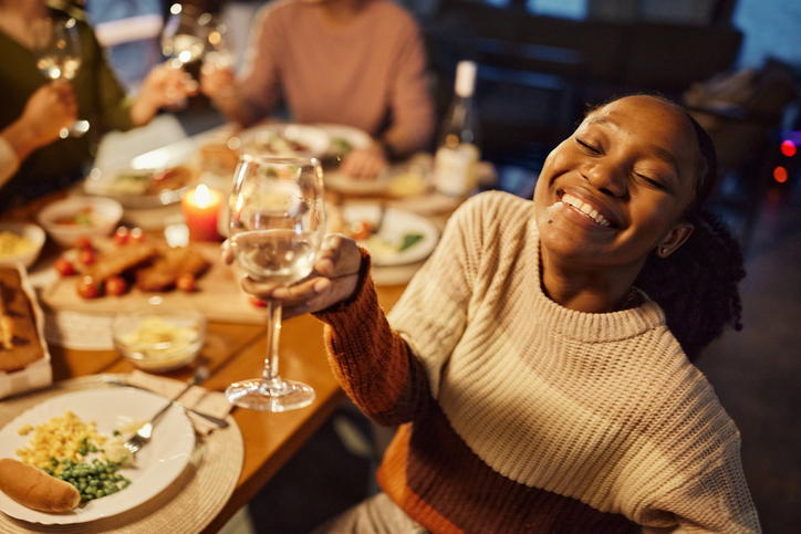 Happy black woman enjoying in dinner with her friends at dining table.