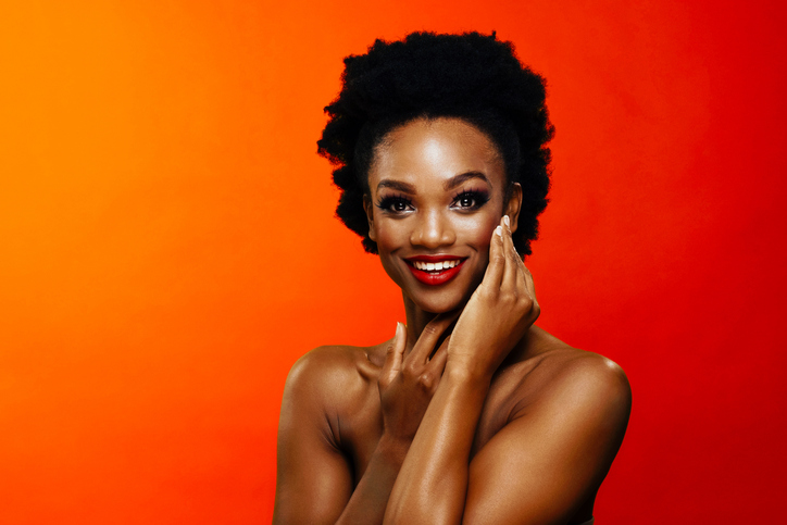 Beautiful African American Black woman touching glowing face with red lipstick.