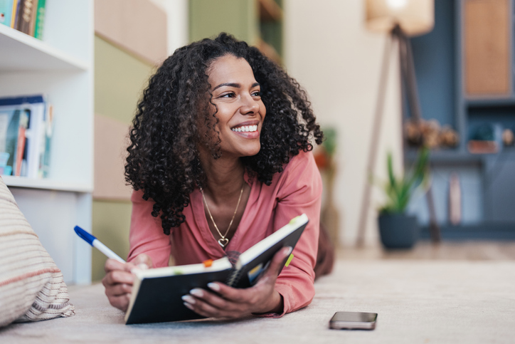 Smiling woman with a journal at home