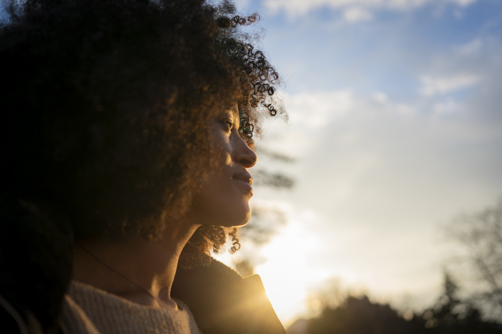 Young woman enjoying sunset outdoors looking away