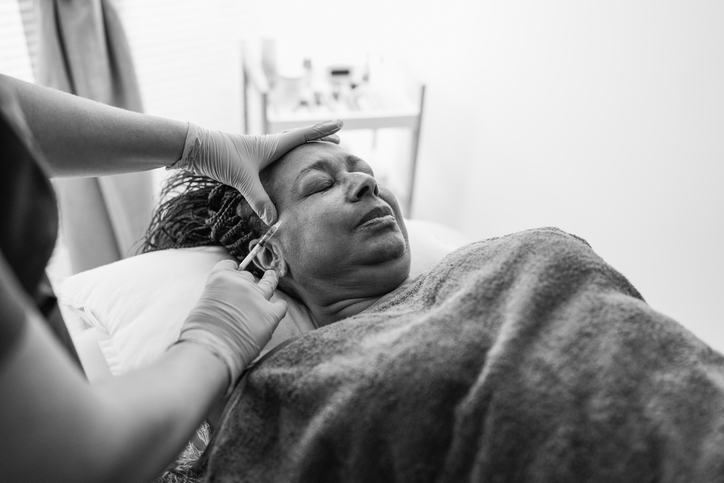 Senior african woman doing botox treatment inside private medical clinic - Beauty trends and anti aging concept