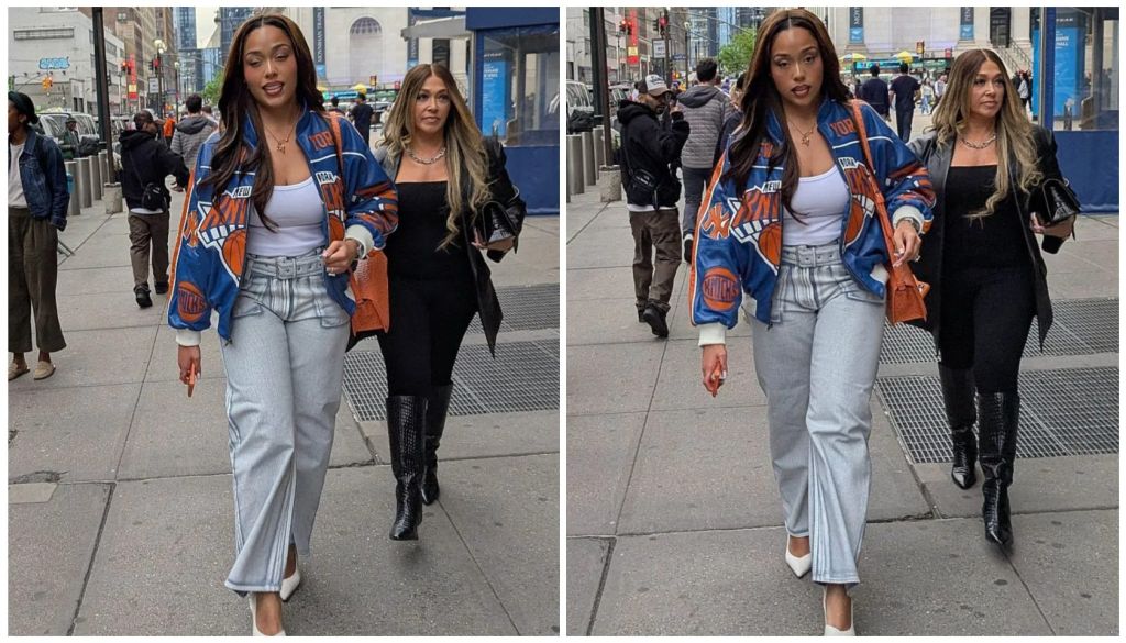 Two young women walking together on a city street, one wearing a blue and orange patterned jacket and the other in a black outfit.
