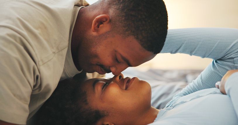 Love, morning and nose touch with black couple in bed at apartment together for bonding or connection. Moment, rest and wake up with happy people in bedroom of home for break, holiday or romance