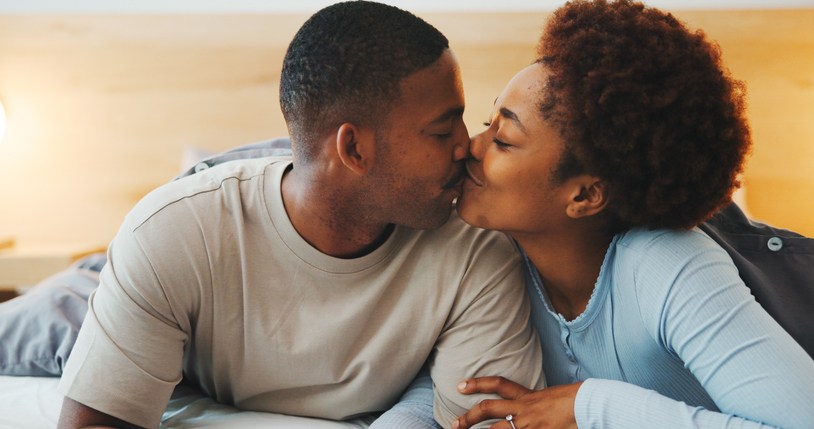 Wake up, kiss or couple in bed with love, partner care or bonding together in connection. Tender, loyalty or African people with affection, romantic moment or morning routine in healthy relationship.