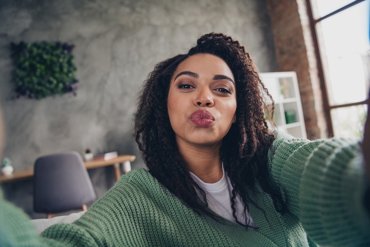 Photo of lovely young girl kissing take selfie photo dressed green knitted garment spacious house indoors room
