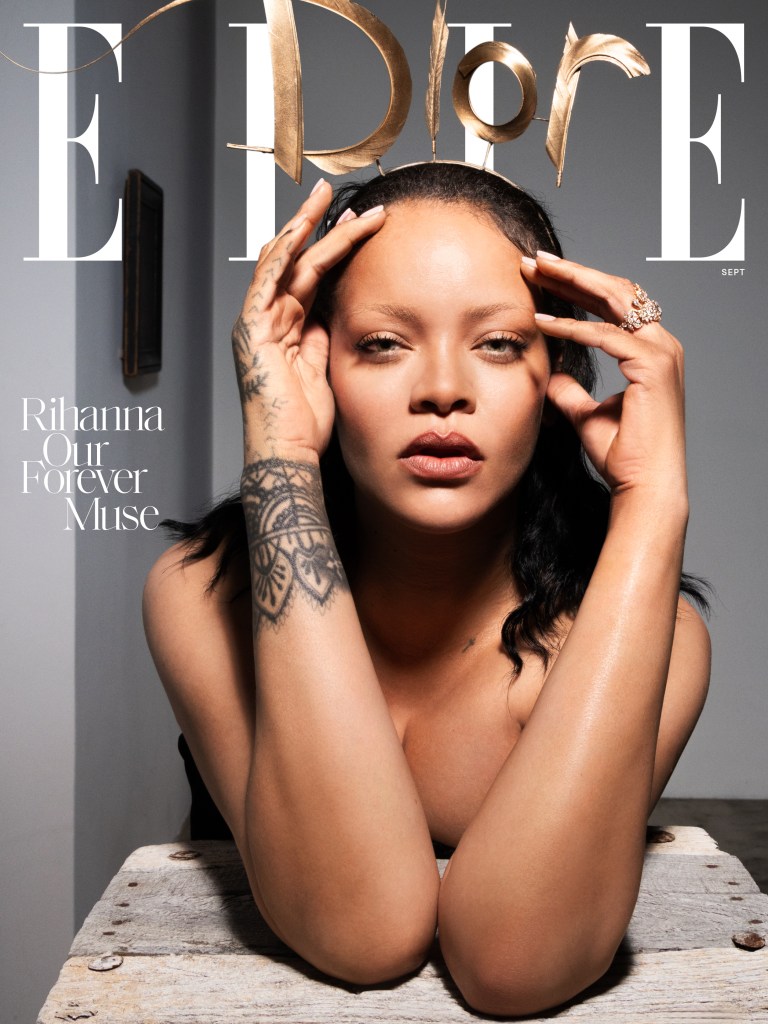 A close-up portrait of a woman with dark hair and tattoos on her arms, looking directly at the camera with a serious expression.