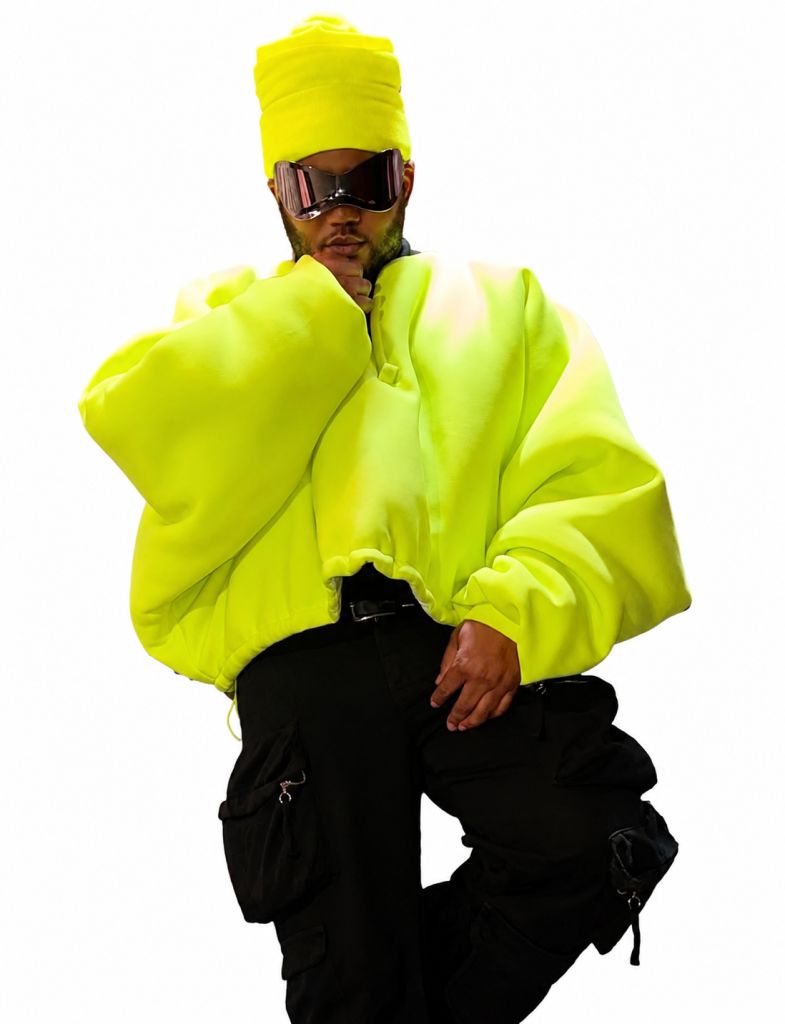 A person wearing a bright neon yellow hooded jacket and sunglasses, standing against a white background.