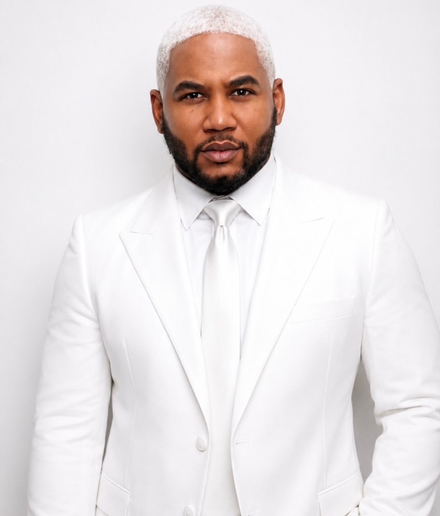 A well-dressed man with a white suit and beard looking directly at the camera.