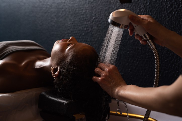 Happy woman is enjoying while getting hair wash in spa salong.