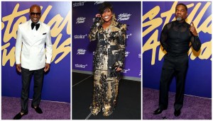 Three celebrities posing on a purple carpet at the Stellar Awards event, wearing formal attire including a white tuxedo, a gold and black patterned outfit, and a black suit.